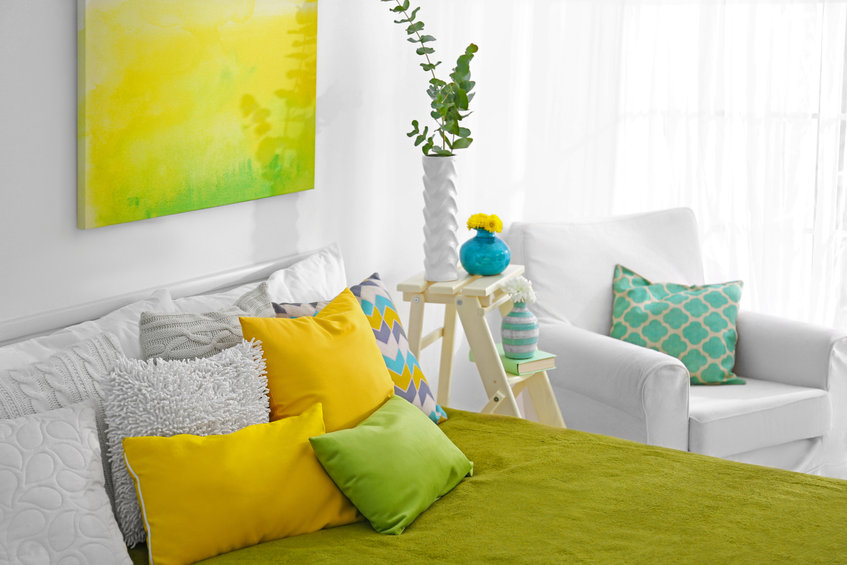 Colorful guest bedroom with chair, book, and plants.
